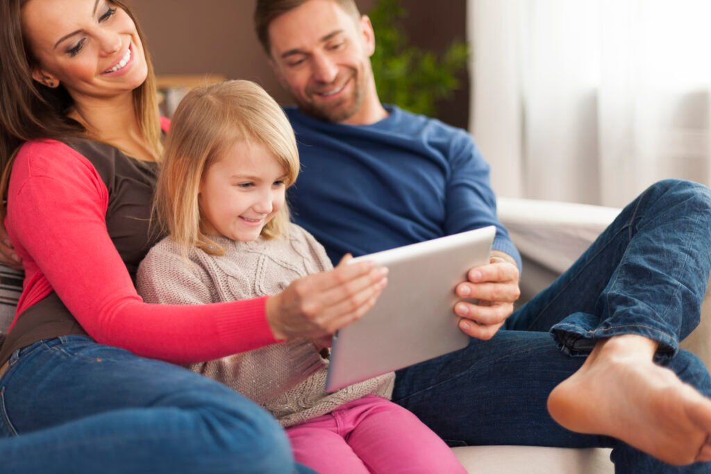 Smiling family using digital tablet at home